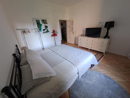 een slaapkamer met een bed, een ladekast en een televisie bij Serenissima Retro Apartment in Muggia