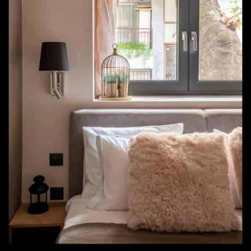 a bed with white pillows and a window with a bird cage at CITY Loft Lux in Thessaloniki