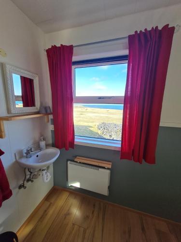 a bathroom with a sink and a window with a view at Brimilsvellir Cottage in Snæfellsbær