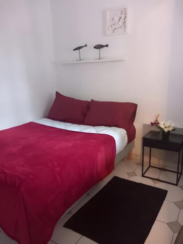 a bed with a red blanket and a table at Manoir du Casino in Cabourg