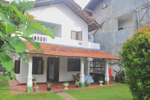 a white house with an orange roof at Talalla Bay Inn Beach Bungalow in Talalla
