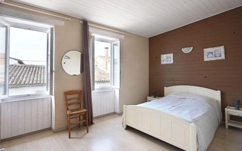 a bedroom with a white bed and two windows at Villa des Ormeaux in Les Moulins de la Boire