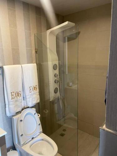 a bathroom with a toilet and a shower with towels at Comfy Apt, Rooftop Lounge, Pool in Santo Domingo