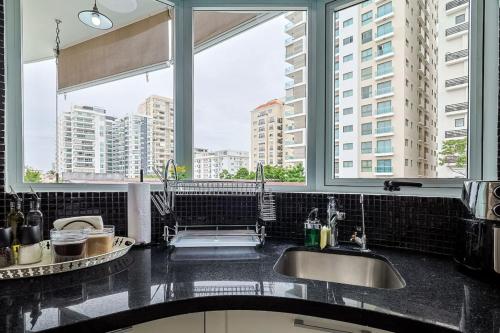 a kitchen with two sinks and two large windows at Comfy 1BR Apt, Centric Full AC in La Julia