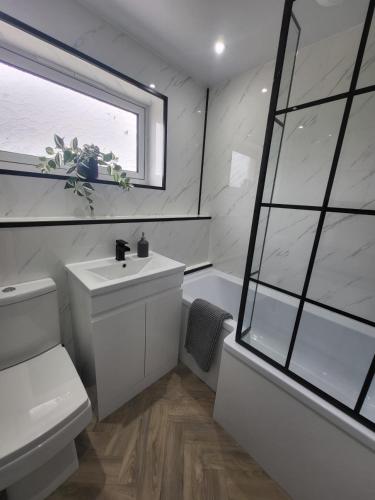 a bathroom with a sink and a toilet and a window at The MacIntyre - Coorie Doon Stays in Kilmarnock