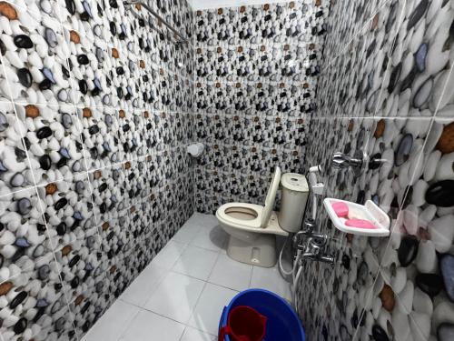 a bathroom with a toilet and a tiled wall at Hotel Tayef Zigatola in Dhaka