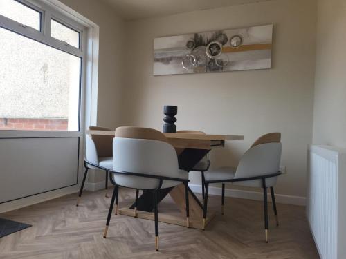 a dining room with a table and chairs and a window at The MacIntyre - Coorie Doon Stays in Kilmarnock