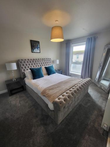 a bedroom with a large bed with blue pillows at The MacIntyre - Coorie Doon Stays in Kilmarnock