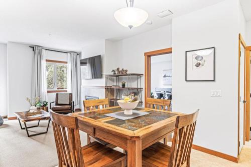 Un comedor con mesa y sillas de madera. en Chic 1BR City Nest Heated Parking and Hot Tub and Pool, en Canmore