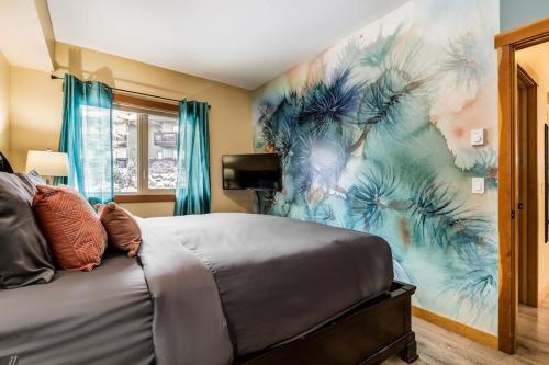 een slaapkamer met een bed met een schilderij aan de muur bij 3BR Rockies Condo Heated Pool and Hot Tub in Canmore