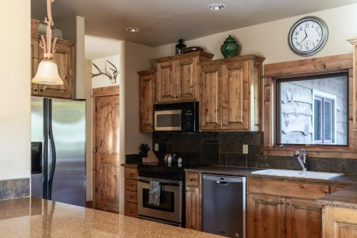 a kitchen with wooden cabinets and a clock on the wall at Twin Lift Lodge in Big Sky Mountain Village