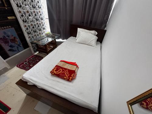 a bed with white sheets and a red pillow on it at Hotel Tayef Zigatola in Dhaka