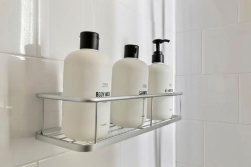a shelf in a bathroom with four bottles on it at The Lexington - Serene Apartment, 5 min to DC with Free Parking and Metro in Arlington