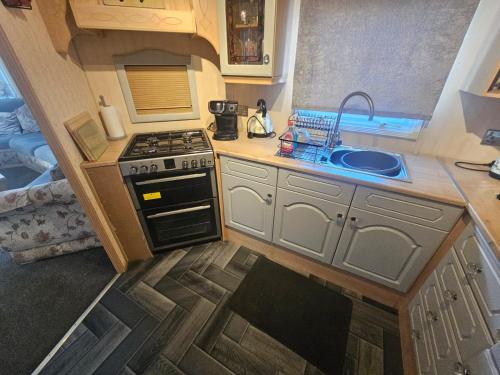eine kleine Küche mit Herd und Spüle in der Unterkunft Goldensands in Foryd