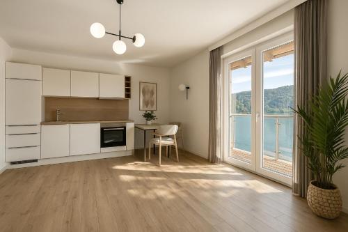 a kitchen with a table and a large window at Lake Lodge Ossiacher See in Annenheim