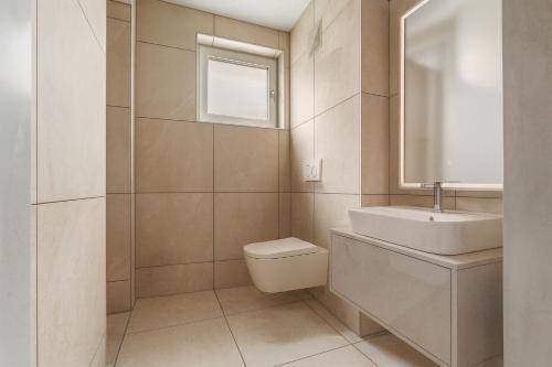 a bathroom with a sink and a toilet and a mirror at Lake Lodge Ossiacher See in Annenheim