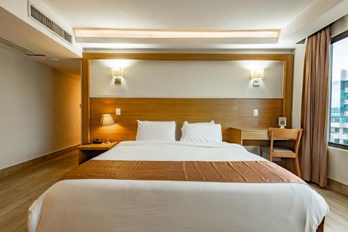 a hotel room with a large bed and a desk at Weston Suites Hotel in Santo Domingo