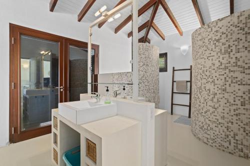 ein weißes Badezimmer mit Waschbecken und Spiegel in der Unterkunft 3bdr, with tropical garden & pool in Kralendijk! in Kralendijk