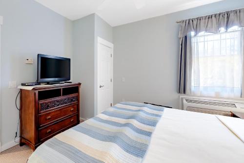 Northeast HarborにあるThe Colonels Suites Unit 1のベッドとドレッサーの上にテレビがある寝室