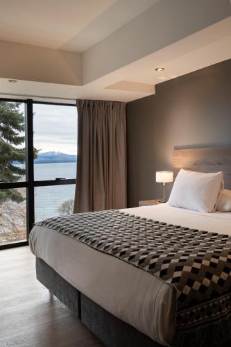 a bedroom with a large bed and a large window at Hotel Alt Interlaken in San Carlos de Bariloche