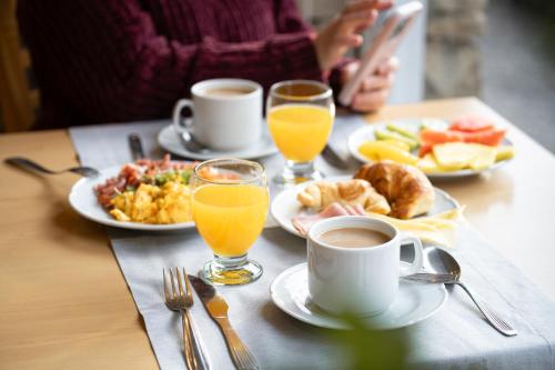 a table topped with plates of breakfast food and orange juice at Hotel Alt Interlaken in San Carlos de Bariloche