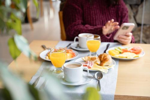 a person sitting at a table with breakfast foods and drinks at Hotel Alt Interlaken in San Carlos de Bariloche