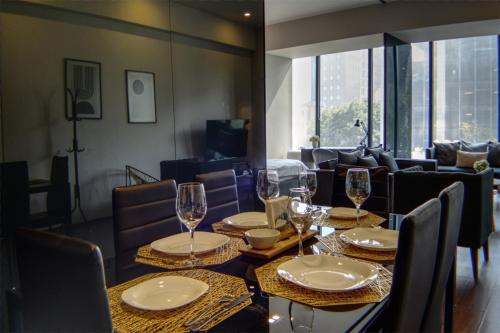 a dining room with a table with glasses and chairs at Reforma 284 King Size SUITE Swimming Pool, Parking & Kitchen in Mexico City