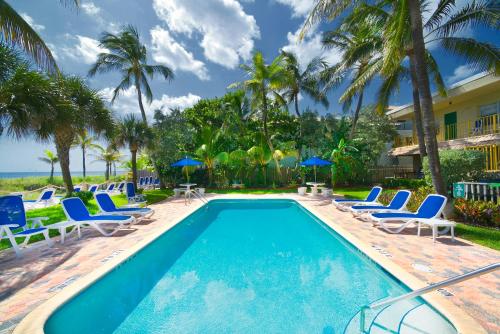 ein Swimmingpool mit Stühlen und Sonnenschirmen in der Unterkunft Tropic Seas Resort in Fort Lauderdale