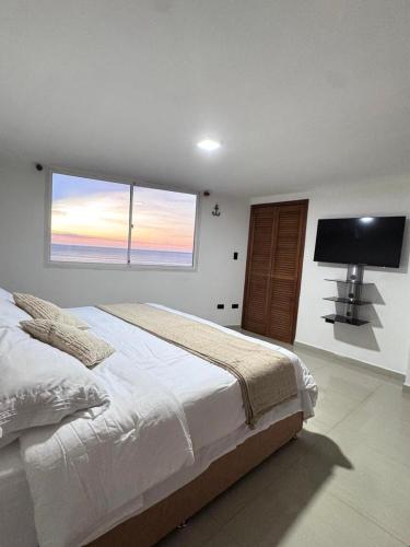 Un dormitorio con una cama grande y un televisor de pantalla plana. en Entire home in Lechería, Venezuela, en El Morro de Barcelona