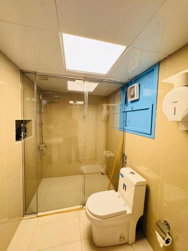 a bathroom with a toilet and a glass shower at Vogue Inn Abu Dhabi in Abu Dhabi