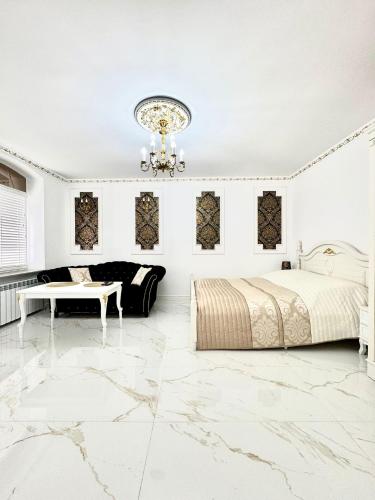 a white bedroom with a bed and a chandelier at Apartament Królewski in Gniezno