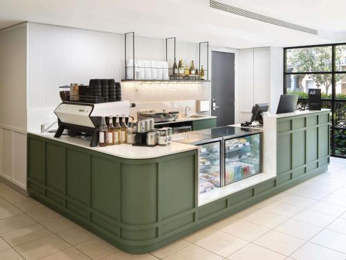 a kitchen with green cabinets and a counter top at Mercure Sydney Macquarie Park in Sydney