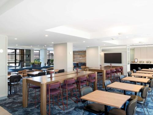 a dining room with tables and chairs and a flat screen tv at Mercure Sydney Macquarie Park in Sydney