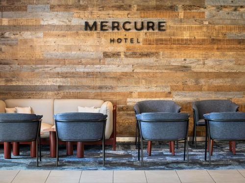 a group of chairs and a hotel sign on a wall at Mercure Sydney Macquarie Park in Sydney