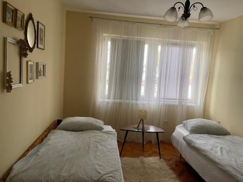 two beds in a room with a window and a table at Stan na dan Gradiška/Bos. Gradiška in Bosanska Gradiška