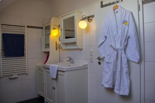 a white bathroom with a robe hanging on the wall at Inselblume 07 - Ferienwohnung mit Hund an der Reiterkoppel in Neue Tiefe Fehmarn