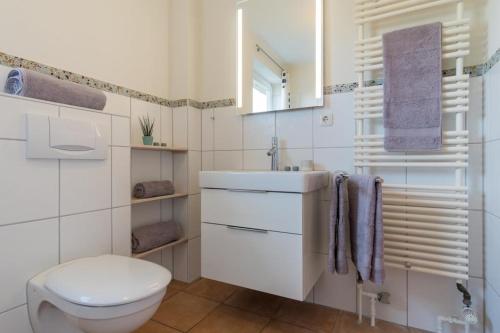 a white bathroom with a toilet and a sink at Inselblume 77 - Ferienwohnung Inselzeit in Burg auf Fehmarn in Burg auf Fehmarn