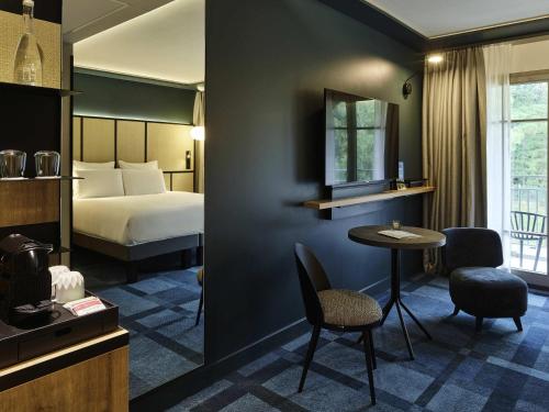 a hotel room with a bed and a table and chairs at Mercure Hôtel Le Touquet in Le Touquet-Paris-Plage