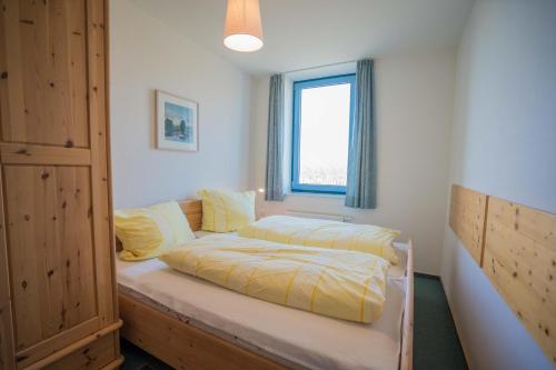 une chambre avec un lit et une fenêtre dans l'établissement Inselblume 14 - Blaue Ferienwohnung mit Balkon am Südstrand, à Burgtiefe auf Fehmarn 