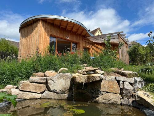 a wooden house with a pond in front of it at Au blé dormant in Wihr-au-Val