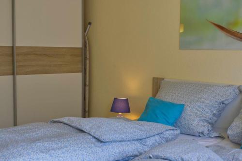 a bedroom with a bed with blue sheets and a lamp at Inselblume 38 - Zentrale Ferienwohnung in Burg mit Garten in Burg auf Fehmarn