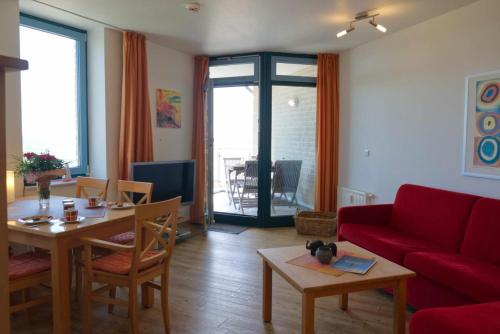 a living room with a red couch and a table at Inselblume 01 - Ferienwohnung mit Meerblick und Balkon am Südstrand in Burgtiefe auf Fehmarn 