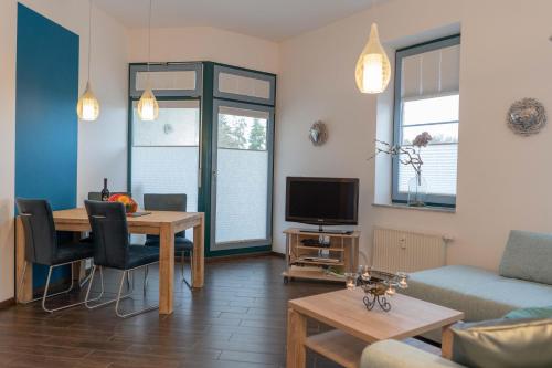 un salon avec un canapé, une table et une télévision dans l'établissement Inselblume 62 - Strandnahe Ferienwohnung am Südstrand, à Burgtiefe auf Fehmarn 