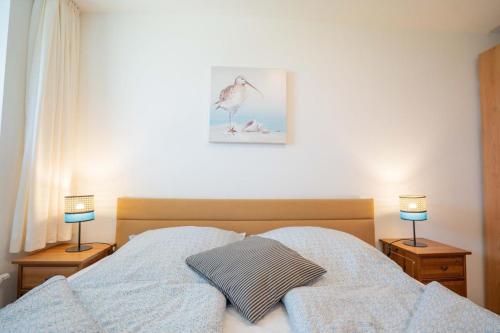 a bedroom with a bed with two lamps on night stands at Inselblume 56 - Ferienwohnung am Südstrand mit Meerblick in Burgtiefe auf Fehmarn 