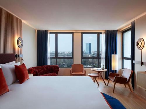 ein Hotelzimmer mit einem großen Bett und großen Fenstern in der Unterkunft SO/ Paris Hotel in Paris
