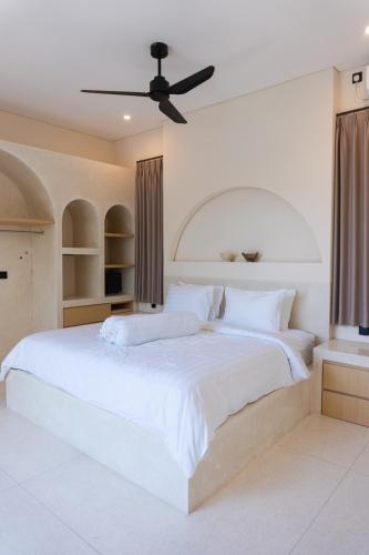 a bedroom with a large white bed with a ceiling fan at VILLA DAHO Mediterranean Elegance in Ungasan