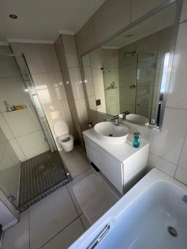 a bathroom with a tub and a sink and a toilet at Secure Estate Home with 24 Hour Surveillance in Cape Town