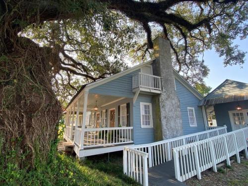 a blue house with a white porch and a tree at Alice by Ravens Keep in Jackson