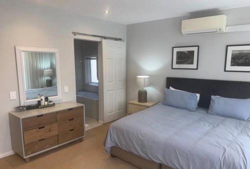 a bedroom with a bed and a sink and a mirror at Secure Estate Home with 24 Hour Surveillance in Cape Town