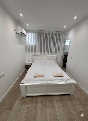a bedroom with a white bed with two pillows on it at Ussishkin Penthouse in Netanya